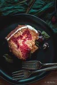 a slice of cranberry orange bundt cake drizzled with cranberry syrup on a plate.