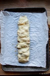 an uncooked apple danish braid on a parchment lined baking sheet