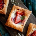 strawberry danishes on a wooden chopping board garnished with fresh mint leaves