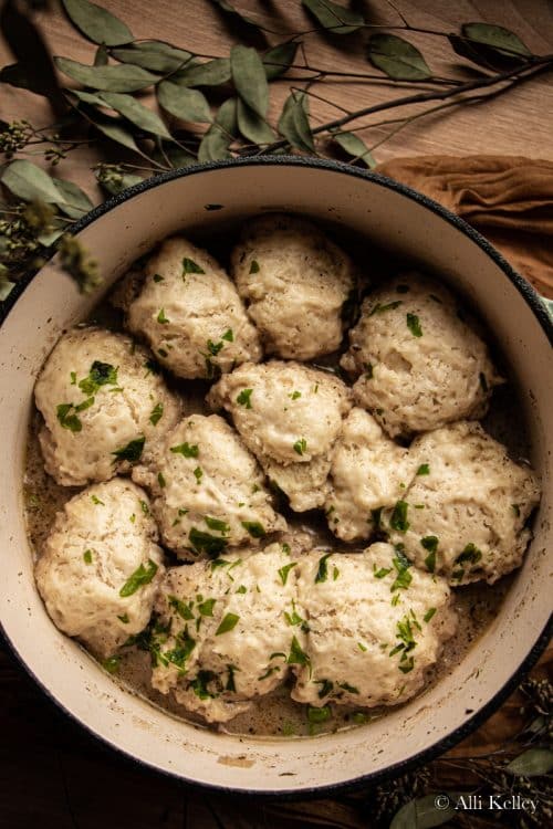 chicken and dumplings in a large pot garnished with fresh herbs