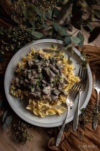 instant pot beef stroganoff with egg noodles and garnished with fresh herbs on a gray plate
