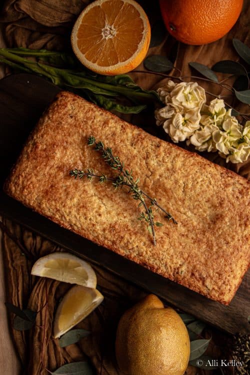 lemon bread garnished with fresh thyme sprigs on a wooden chopping board