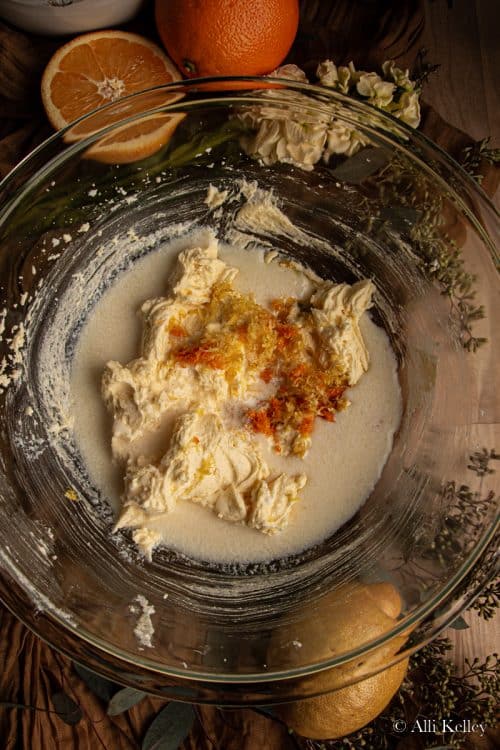 creamed butter and sugar, with milk and orange and lemon zest in a glass mixing bowl