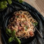 zucchini pasta on a black plate garnished with fresh herbs