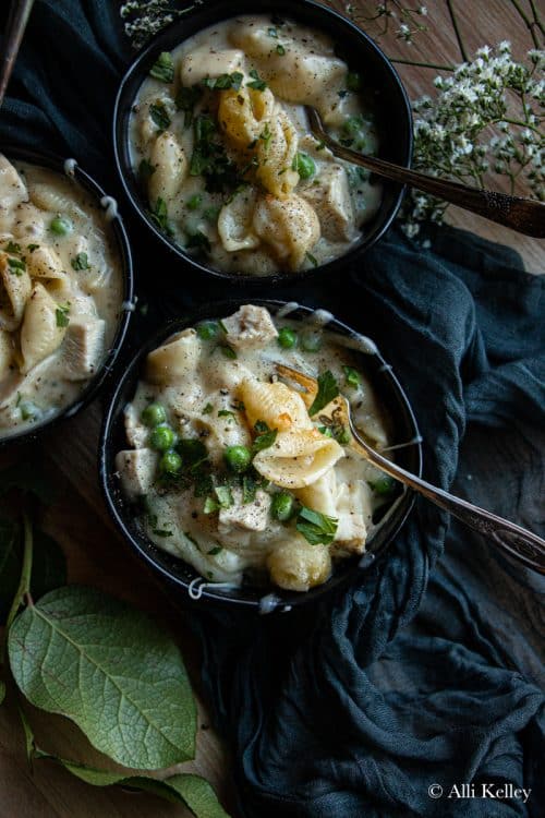 three bowls of chicken pasta casserole topped with fresh herbs