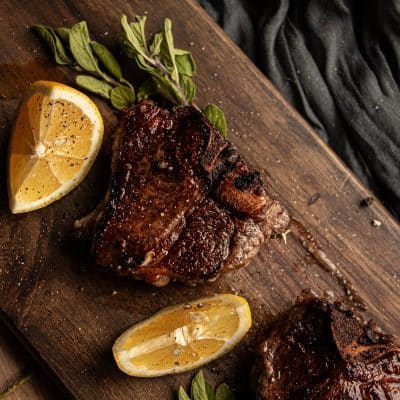 cooked greek lamb chops on a chopping board with lemon wedges