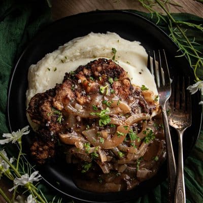 mashed potato and pan friend cube steak topped with onion gravy on a plate