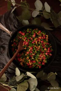 a wooden spoon scooping some veggie medley from a frying pan.