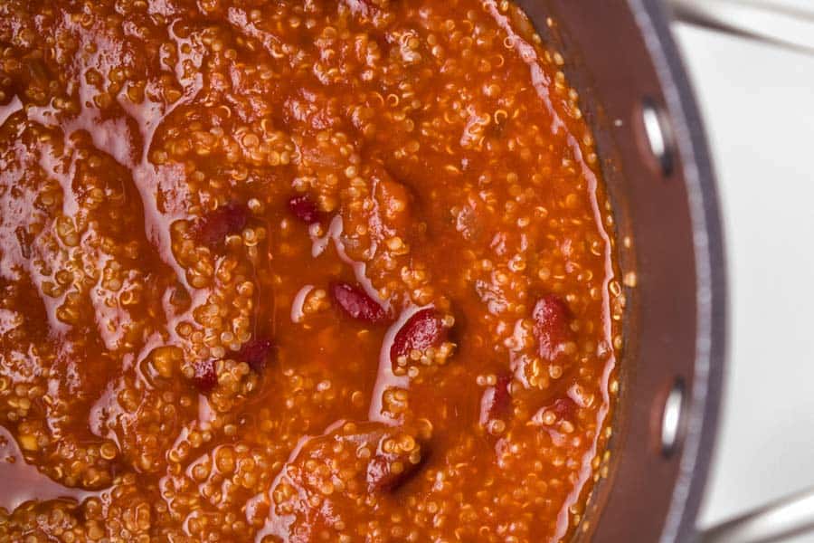 Close-up of a pot filled with thick, red chili—a good vegetarian chili recipe—made with kidney beans and quinoa in a rich tomato-based sauce.